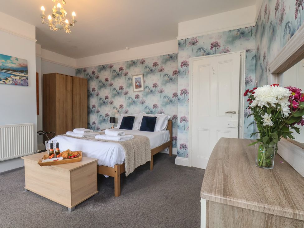 A bedroom with beds, wardrobe and flowers at 30 Prospect Hill in Whitby