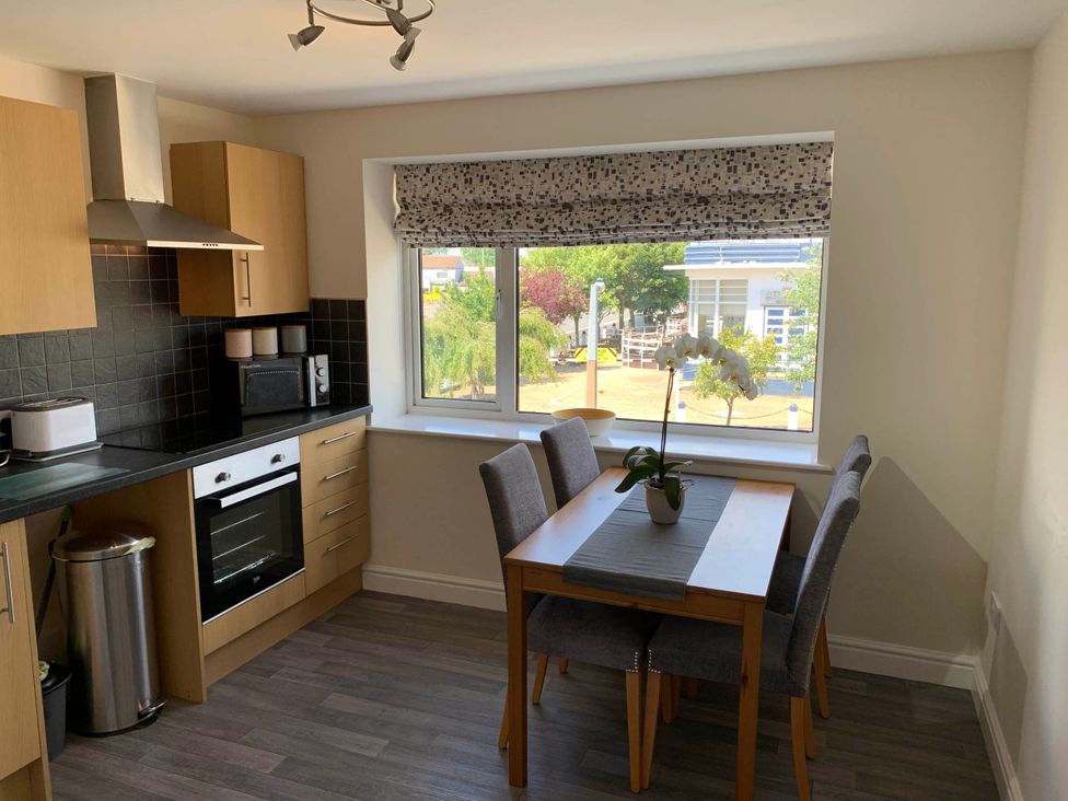 A kitchen with cabinets, a window, a table and chairs at Balcony Apartment near Skegness Beach & Town Skegness