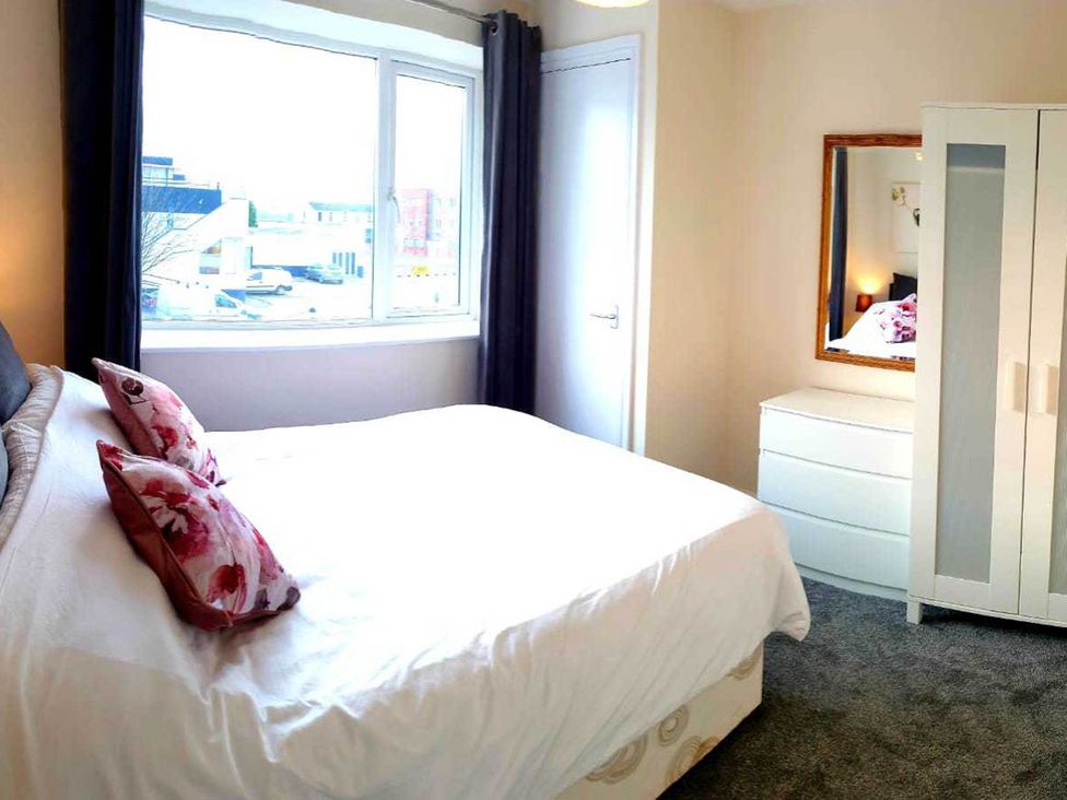 A bedroom with a bed and a wardrobe at Balcony Apartment near Skegness Beach & Town Skegness