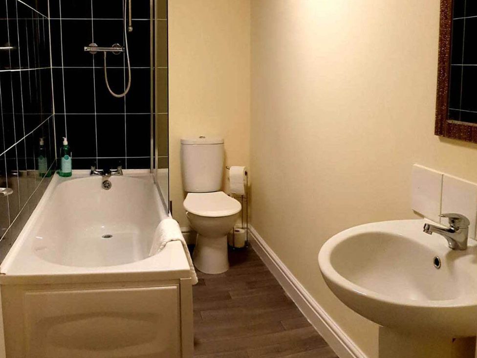 A bathroom with a bathtub, toilet, and sink at Balcony Apartment near Skegness Beach & Town in Skegness