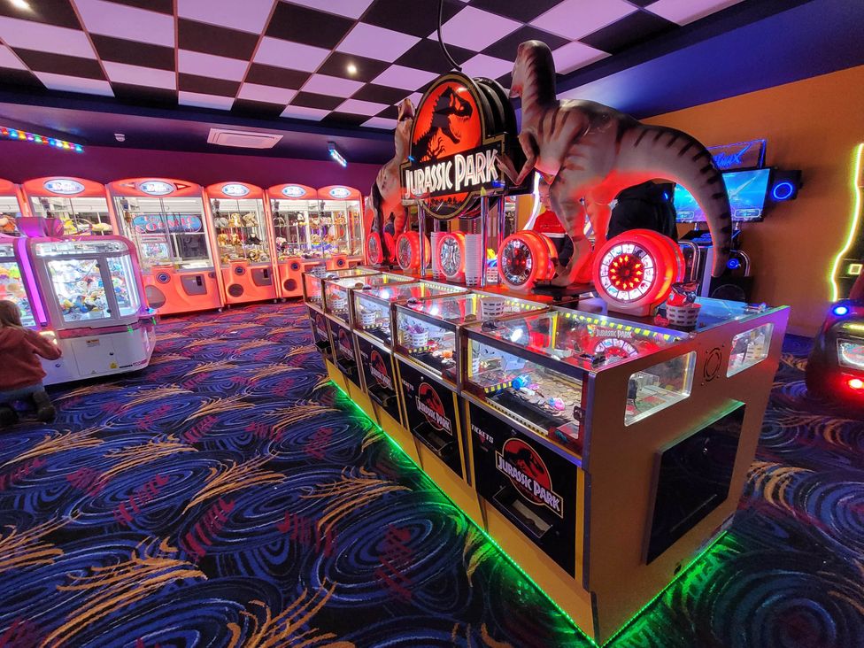 An arcade with various games and a dinosaur statue at St Osyth- Sleeps8-freeparking-wifi-holidaypark in Clacton-On-Sea