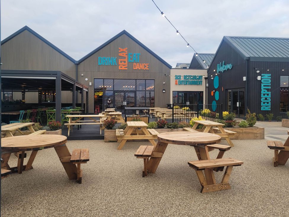 An outdoor area with wooden tables and colorful chairs at St Osyth- Sleeps8-freeparking-wifi-holidaypark, Clacton-On-Sea