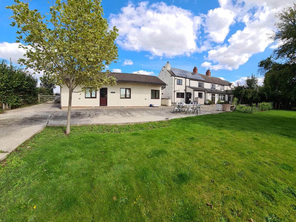 An outdoor view of a house with a tree and patio at Cosy stable conversion between Sheffield & Leeds, Pontefract