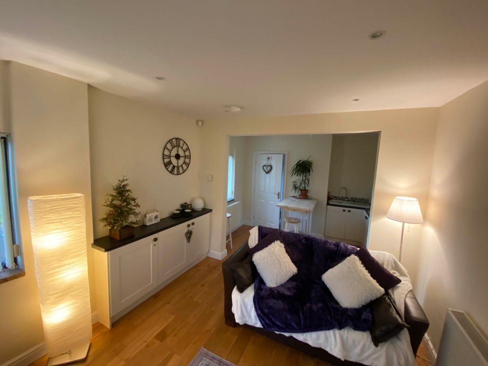 A living room with a sofa and a clock at Cosy stable conversion between Sheffield & Leeds in Pontefract