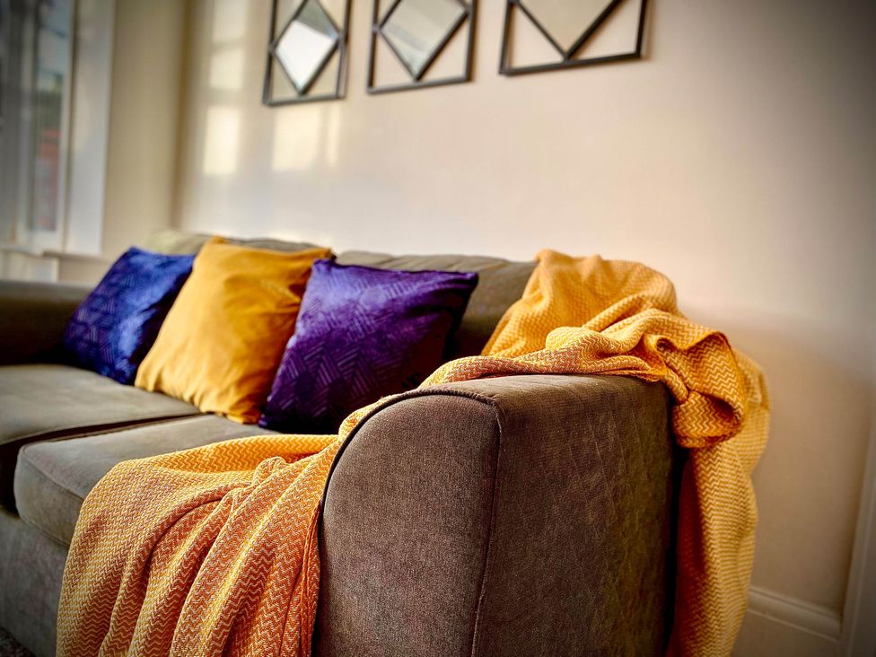 A living room with a sofa and cushions at Family modern 3 bedroom hot tub house Blackpool