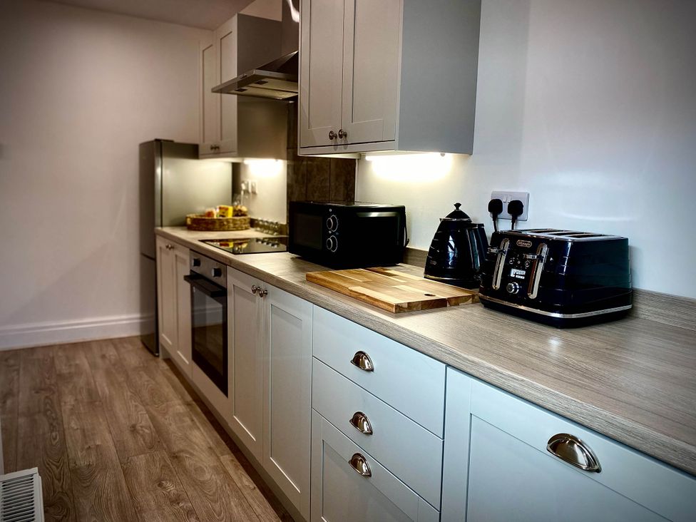A kitchen with appliances including a refrigerator, oven, toaster, and kettle at Family modern 3 bedroom hot tub house Blackpool