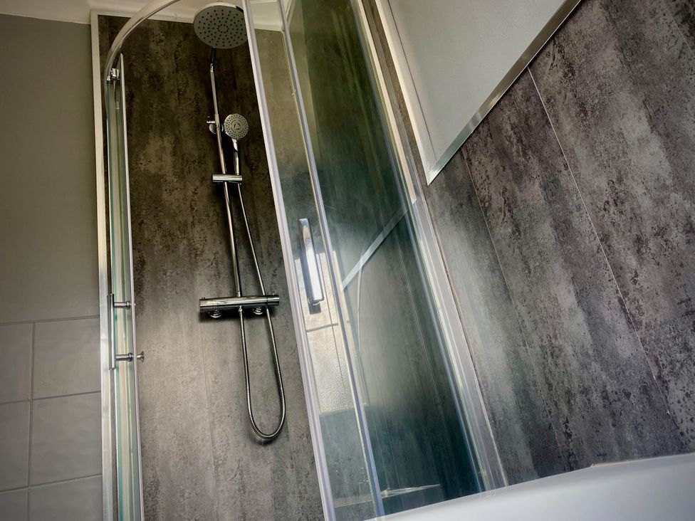 A shower with glass door and showerhead at Family modern 3 bedroom hot tub house in Blackpool