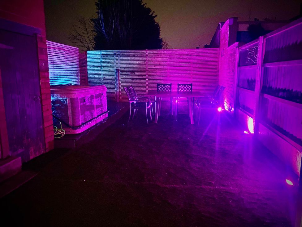 A garden with a hot tub and a table with chairs at Family modern 3 bedroom hot tub house Blackpool