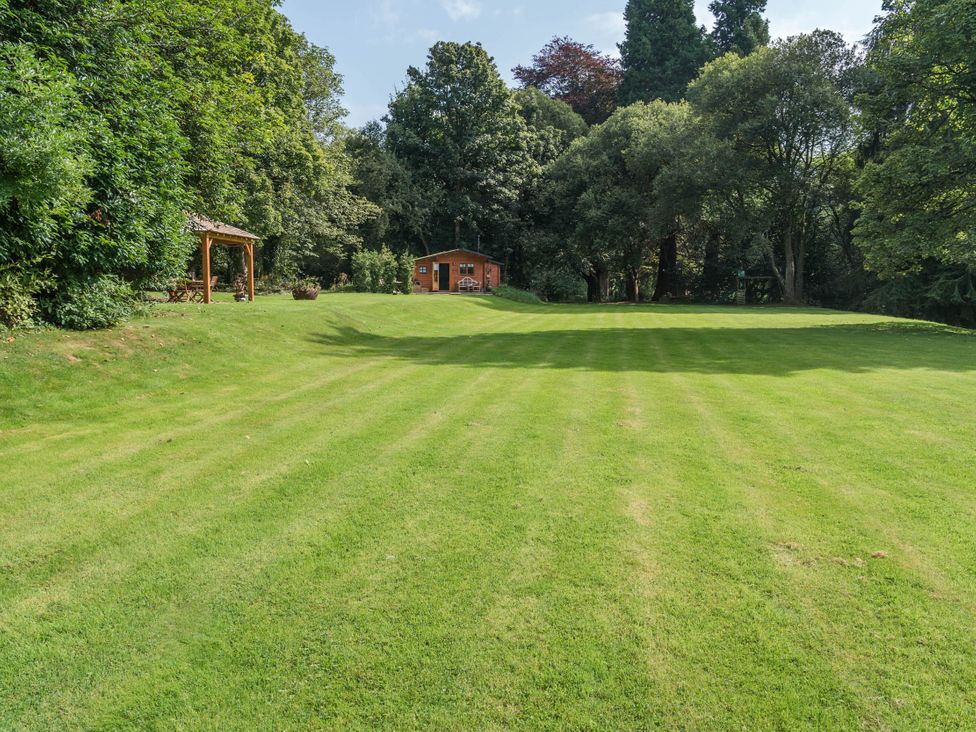 An outdoor area with grass and a garden shed at Cabin for 2 - Wood Burning Hot Tub & Fire, Larkhall