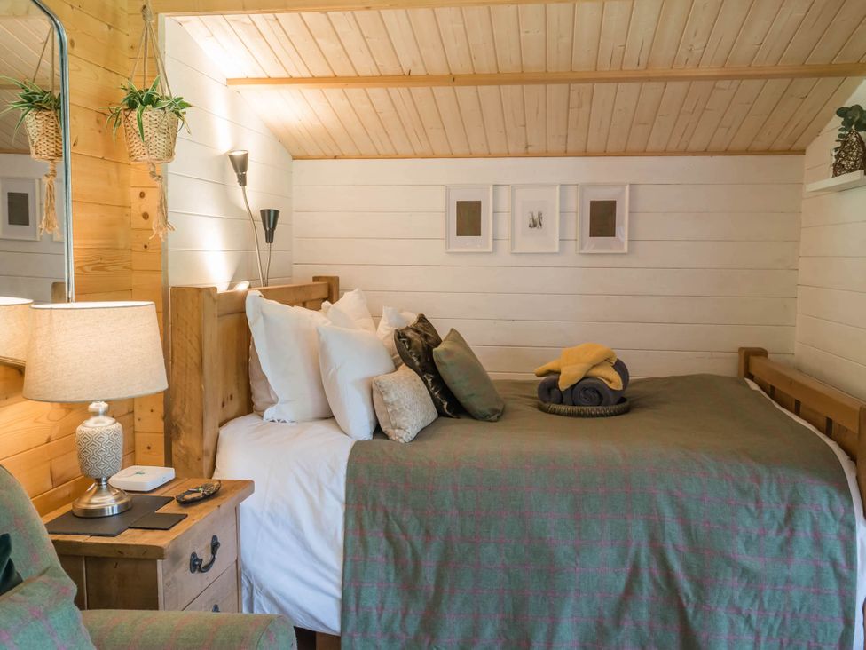 A bedroom with a bed, lamp, and decorative items at Cabin for 2 - Wood Burning Hot Tub & Fire in Larkhall