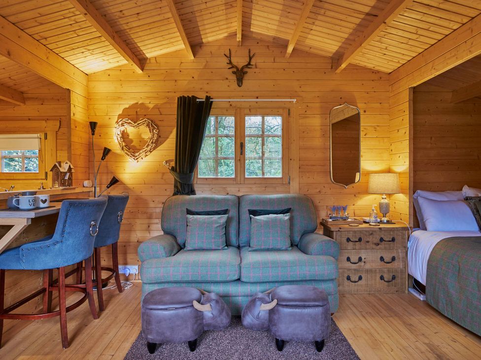 A living room with a sofa and bar stools at Cabin for 2 - Wood Burning Hot Tub & Fire, Larkhall