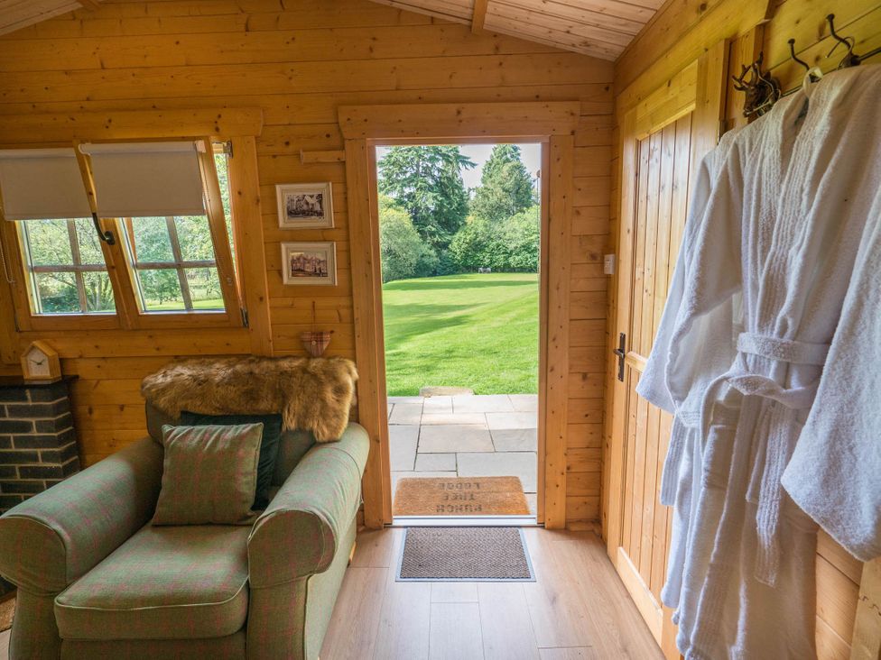 A living room with a sofa and door leading to outdoor area at Cabin for 2 - Wood Burning Hot Tub & Fire in Larkhall