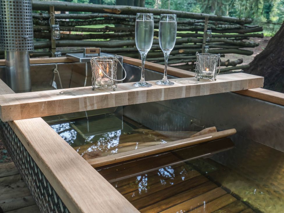 A hot tub with a wooden shelf holding glasses and candles at Cabin for 2 - Wood Burning Hot Tub & Fire Larkhall