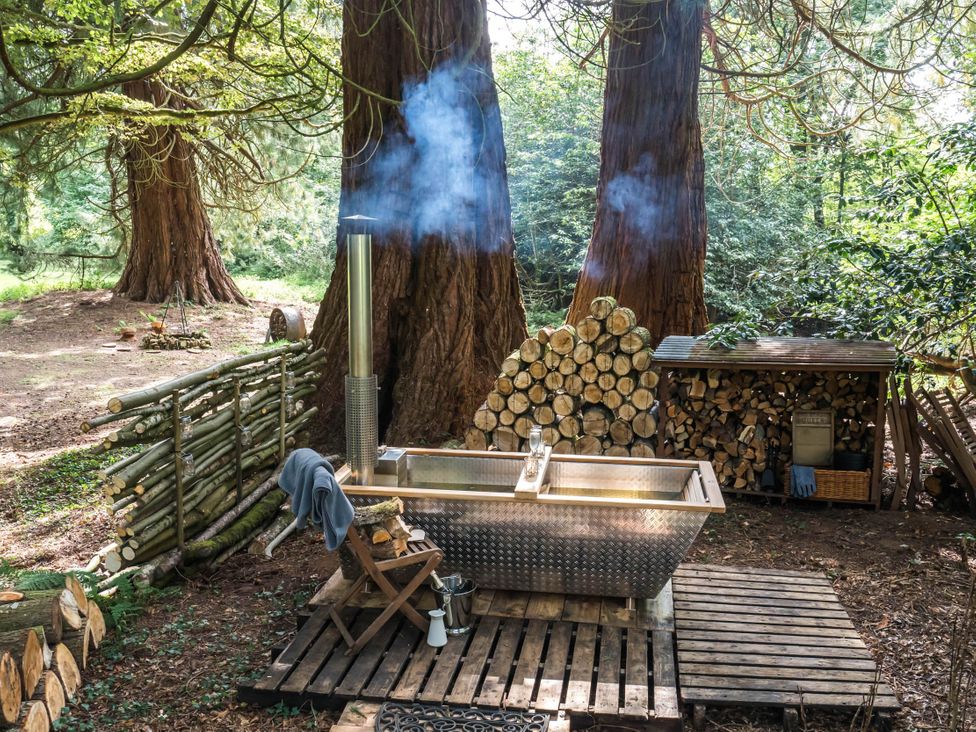An outdoor area with a bath tub and firewood storage at Cabin for 2 - Wood Burning Hot Tub & Fire in Larkhall