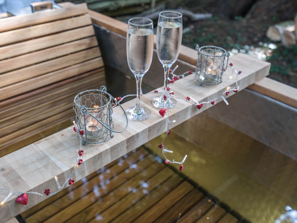 A wooden table with champagne glasses and candles at Cabin for 2 - Wood Burning Hot Tub & Fire Larkhall