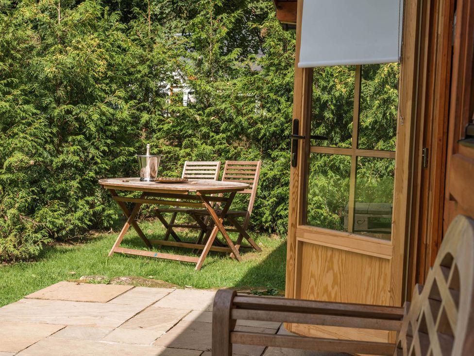 A table with chairs in a garden at Cabin for 2 - Wood Burning Hot Tub & Fire in Larkhall