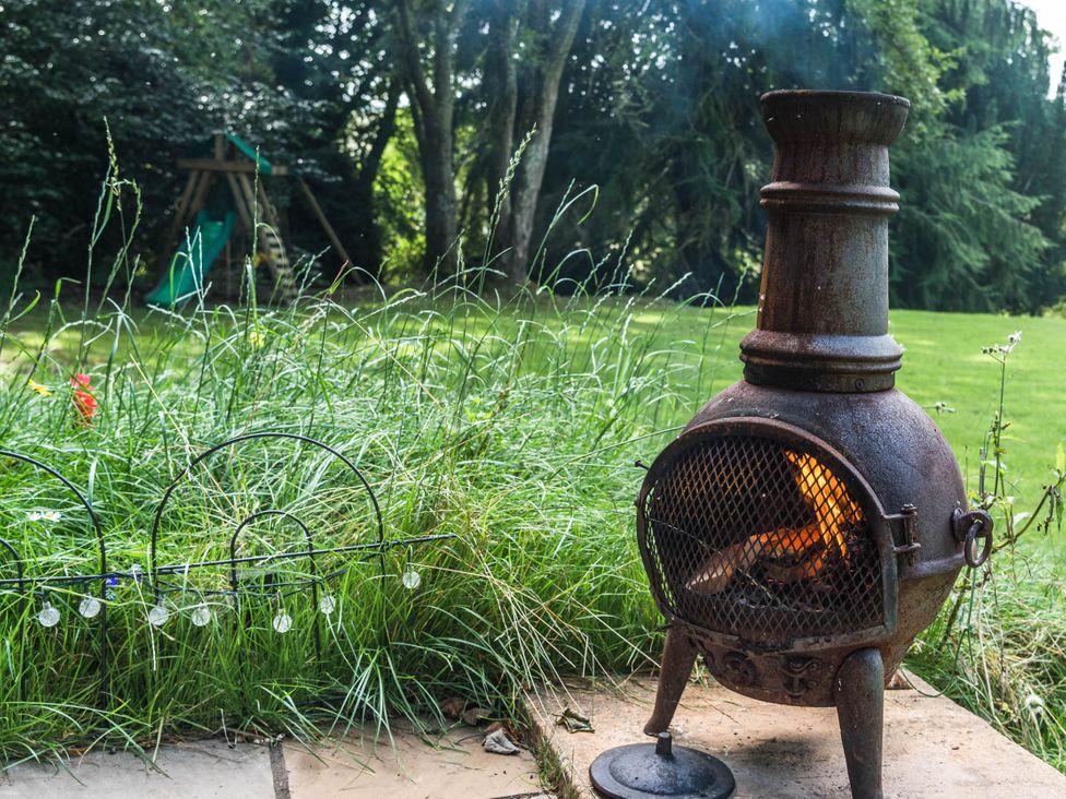 A garden with a chiminea and a playset at Cabin for 2 - Wood Burning Hot Tub & Fire, Larkhall