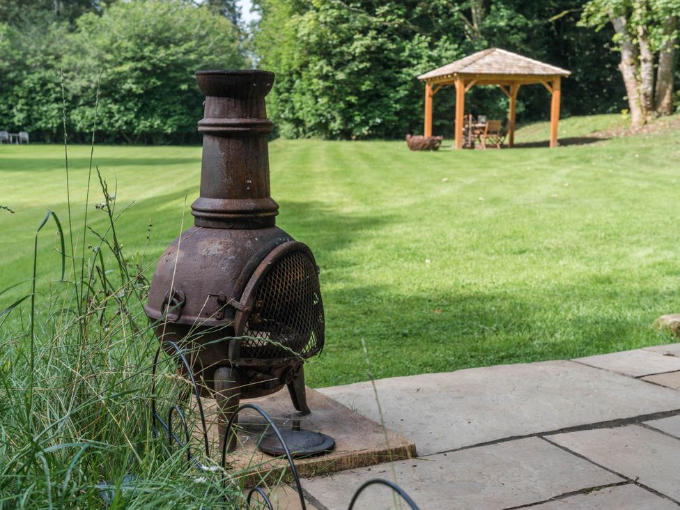 A patio with a chiminey and a gathering area at Cabin for 2 - Wood Burning Hot Tub & Fire Larkhall