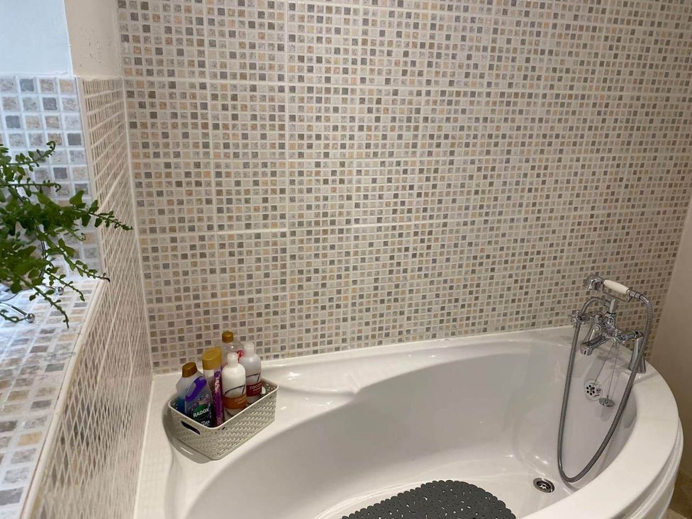 A bathroom with a bathtub and bottles on a shelf at Apartment - Sleeps 2 - Pet friendly - Parking in Ludlow