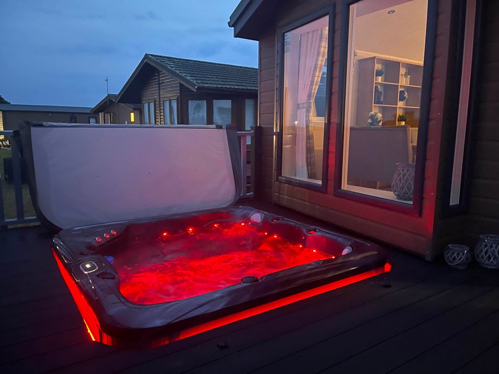 A hot tub on a deck outside a building at Yorkshire view lodge in Wilberfoss