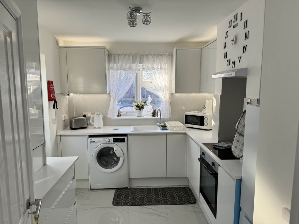 A kitchen with appliances including a washing machine and microwave at Modern 3-Bed Hideaway Near Westgate With Parking, Canterbury