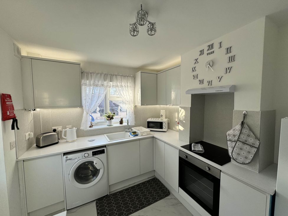 A kitchen with a washing machine, oven, and microwave at Modern 3-Bed Hideaway Near Westgate With Parking, Canterbury
