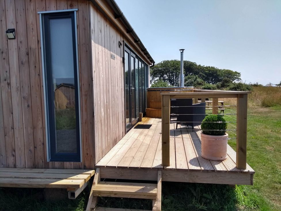 An outdoor patio with a wooden cabin and furniture at Cleeves Cabins 1, Ailsa Luxury Lodge with hot tub, St. John's Town Of Dalry