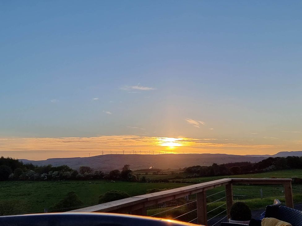 A view of the sunset over hills and fields with wind turbines at Cleeves Cabins 1, Ailsa Luxury Lodge with hot tub, St. John's Town Of Dalry