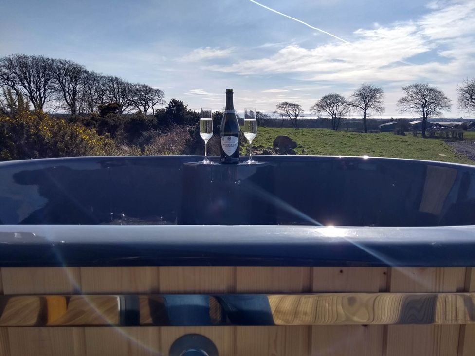 An outdoor hot tub with a champagne bottle and glasses at Cleeves Cabins 2, Arran Luxury Lodge with hot tub St. John's Town Of Dalry