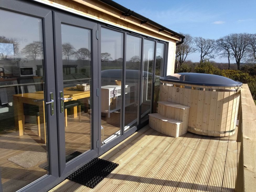 A deck with a hot tub and outdoor seating at Cleeves Cabins 2, Arran Luxury Lodge with hot tub in St. John's Town Of Dalry