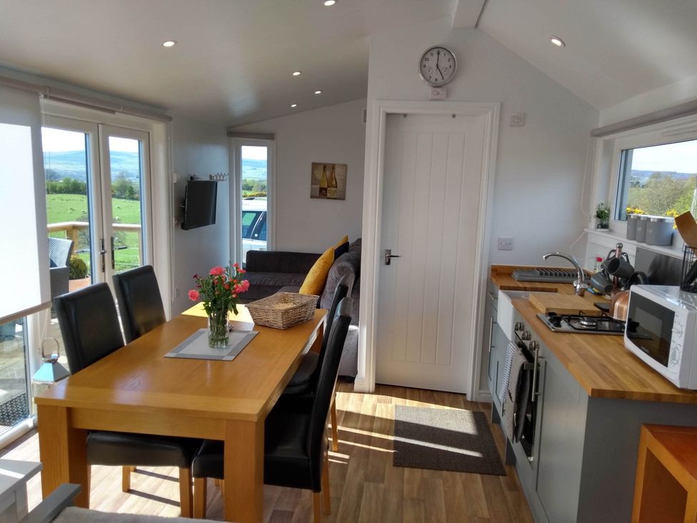 A kitchen with dining table and sofas at Cleeves Cabins 2, Arran Luxury Lodge with hot tub St. John's Town Of Dalry