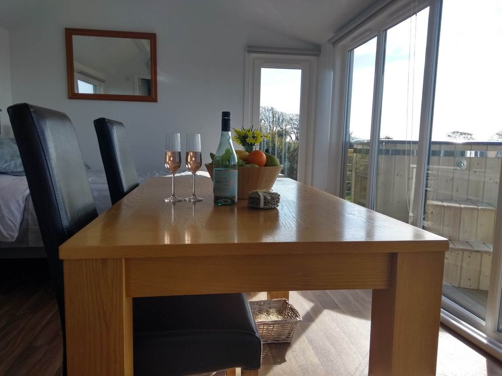A dining table with wine glasses and fruit bowl at Cleeves Cabins 2, Arran Luxury Lodge with hot tub St. John's Town Of Dalry
