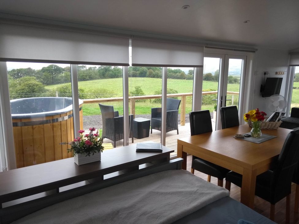 A living room with a dining table and hot tub at Cleeves Cabins 2, Arran Luxury Lodge with hot tub St. John's Town Of Dalry