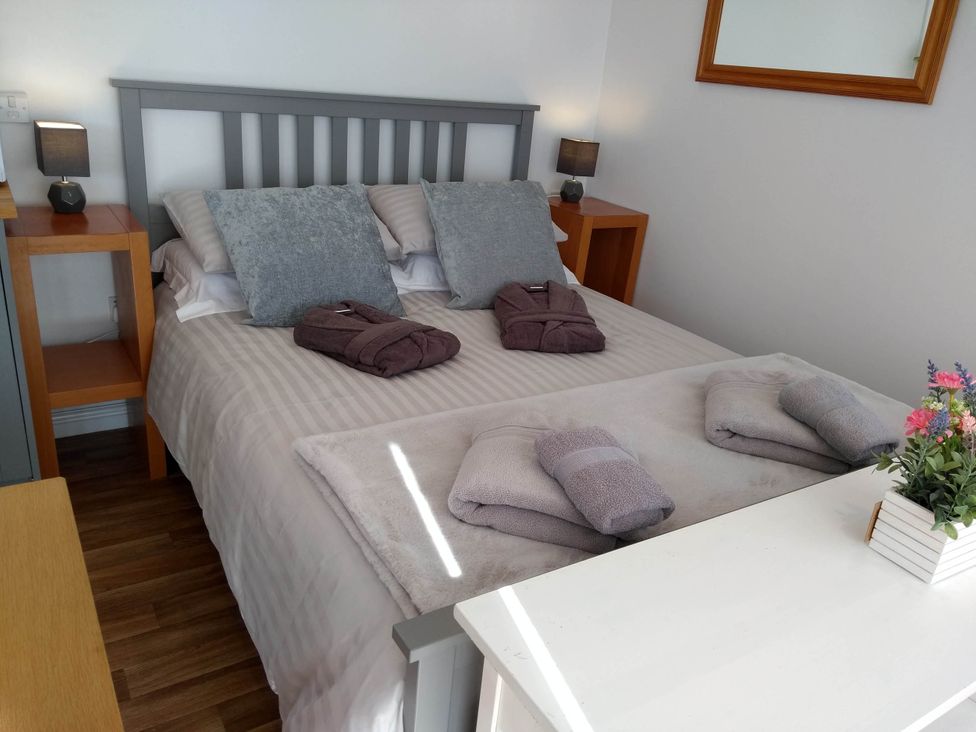 A bedroom with a bed and bedside lamps at Cleeves Cabins 2, Arran Luxury Lodge with hot tub, St. John's Town Of Dalry