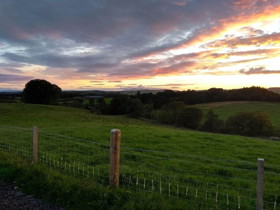 A grassy field with a fence and trees at Cleeves Cabins 2, Arran Luxury Lodge with hot tub, St. John's Town Of Dalry