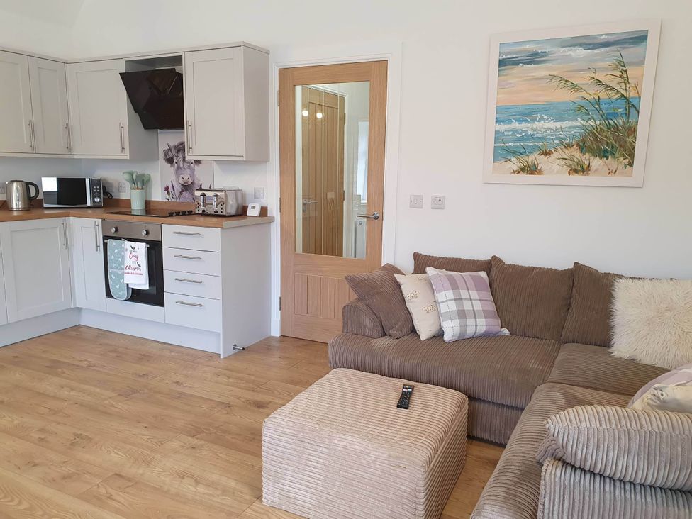 A living room with kitchen and sofa at 2-Bed Barn, Hot Tub & Pet Friendly near Muirkirk