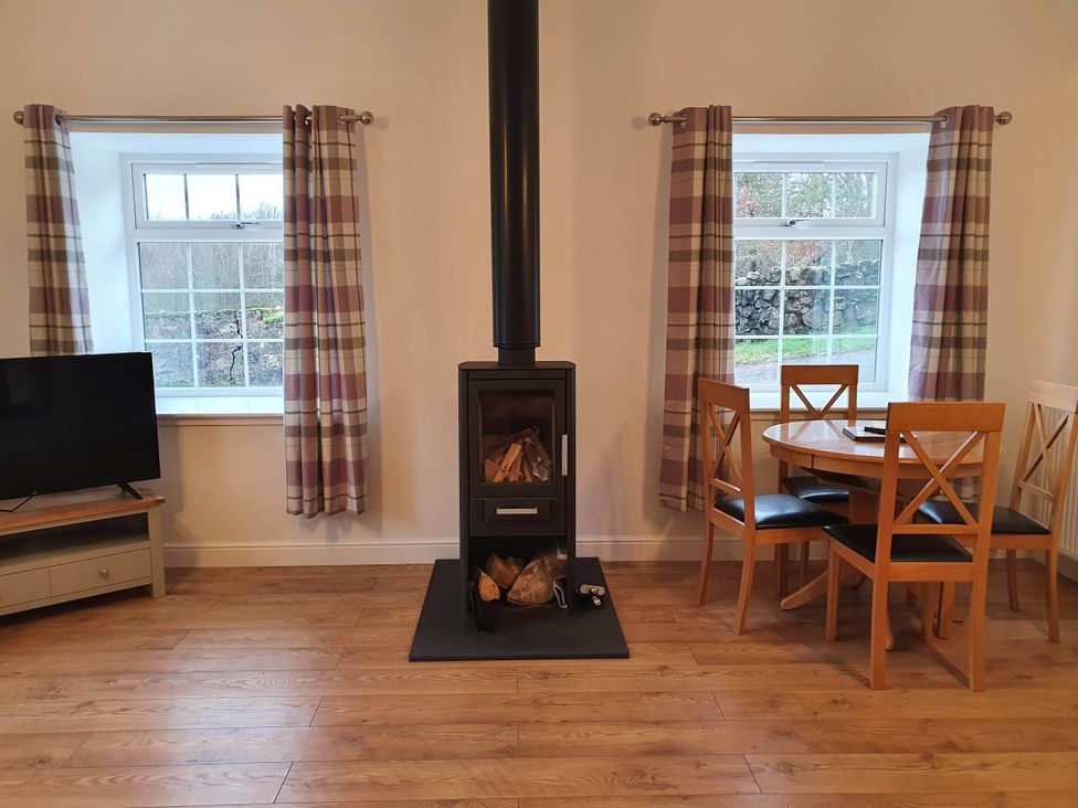 A dining room with a television and a fireplace at 2-Bed Barn, Hot Tub & Pet Friendly near Muirkirk