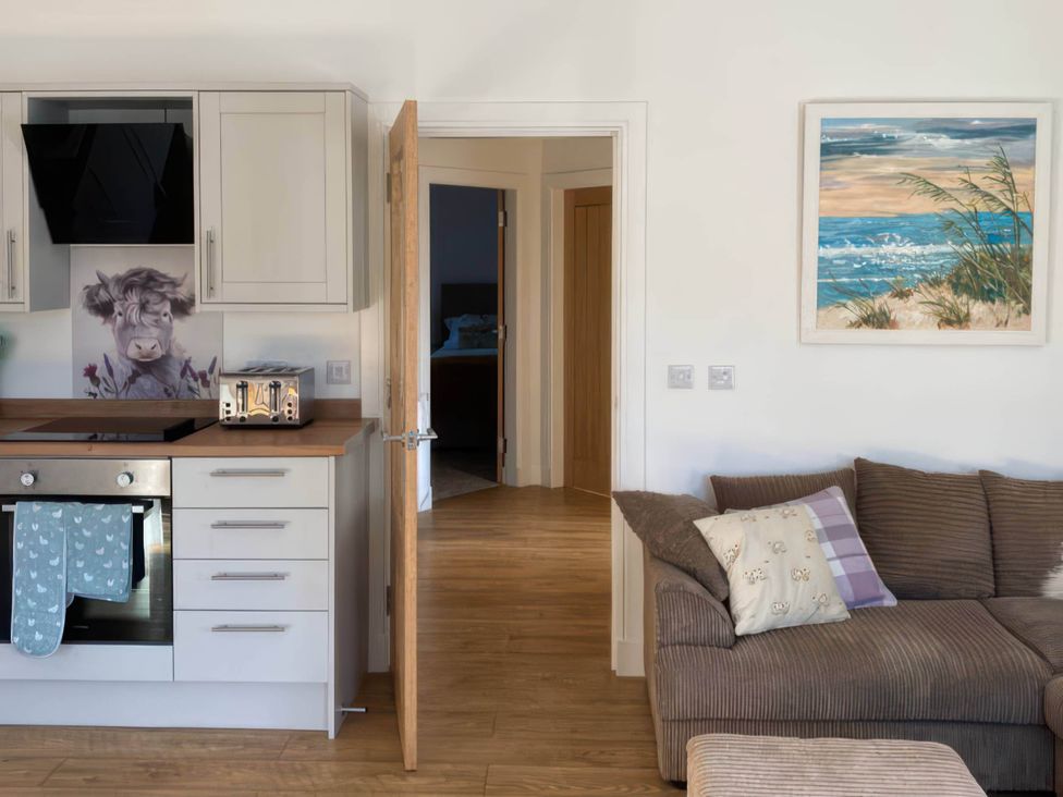 A kitchen with a couch and an open door at 2-Bed Barn, Hot Tub & Pet Friendly near Muirkirk