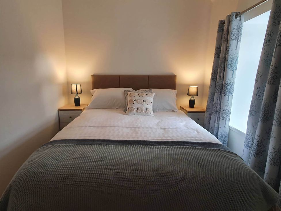 A bedroom with a bed, lamps, and curtains at 2-Bed Barn, Hot Tub & Pet Friendly near Muirkirk
