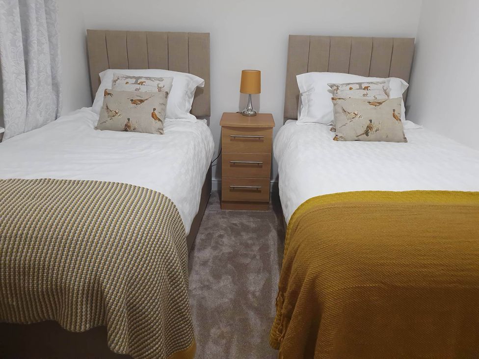 A bedroom with two single beds and a bedside table at 2-Bed Barn, Hot Tub & Pet Friendly near Muirkirk