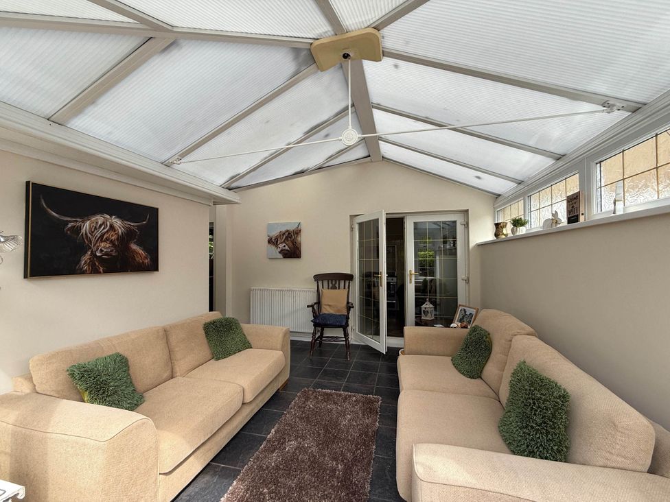 A conservatory with two sofas and an armchair at 3 Bed House - Sleeps 6 - Parking - Garden - Wifi Glynneath