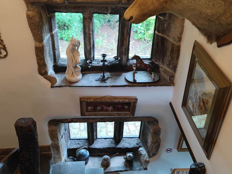 A staircase with windows featuring a statue and a horse figurine at 3 bedroom- Sleeps 6-Greave Farm Todmorden Cottage in Todmorden