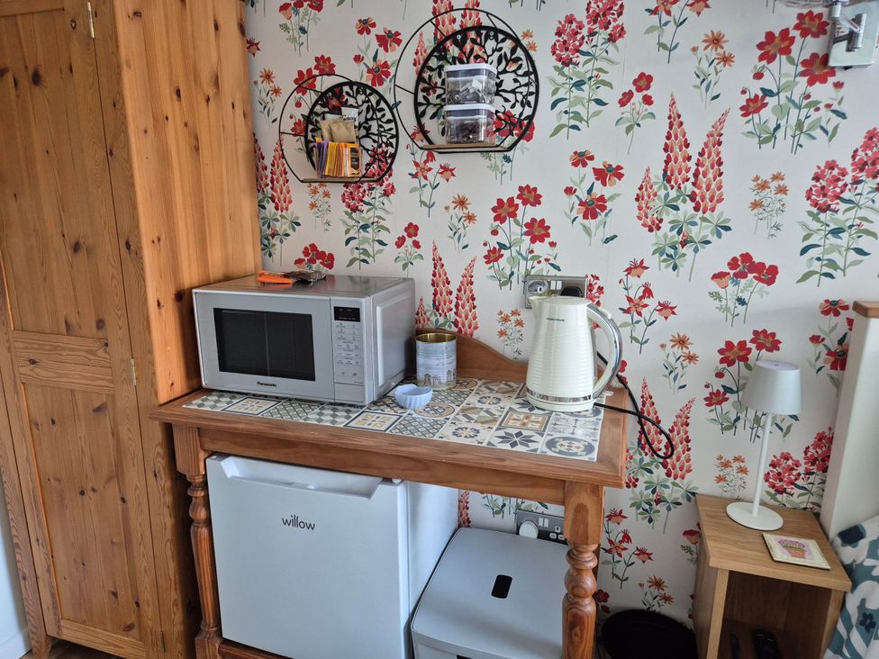 A kitchen area with a microwave and kettle at Flower Garden Studio in Sheringham