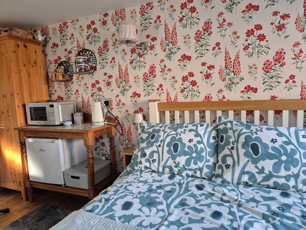 A bedroom with a bed and kitchen appliances at Flower Garden Studio in Sheringham