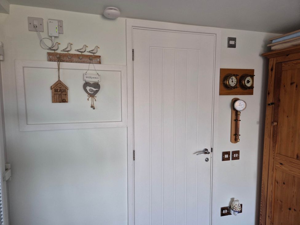 A hallway with a door and decorative items at Flower Garden Studio in Sheringham