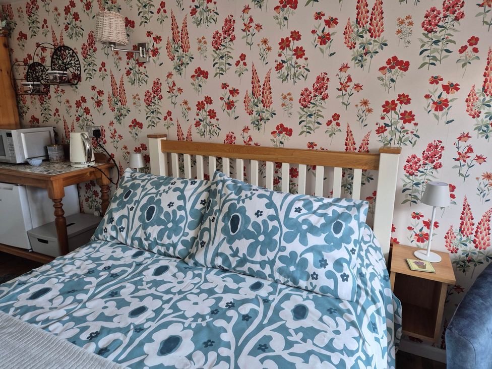 A bedroom with a bed and microwave at Flower Garden Studio in Sheringham