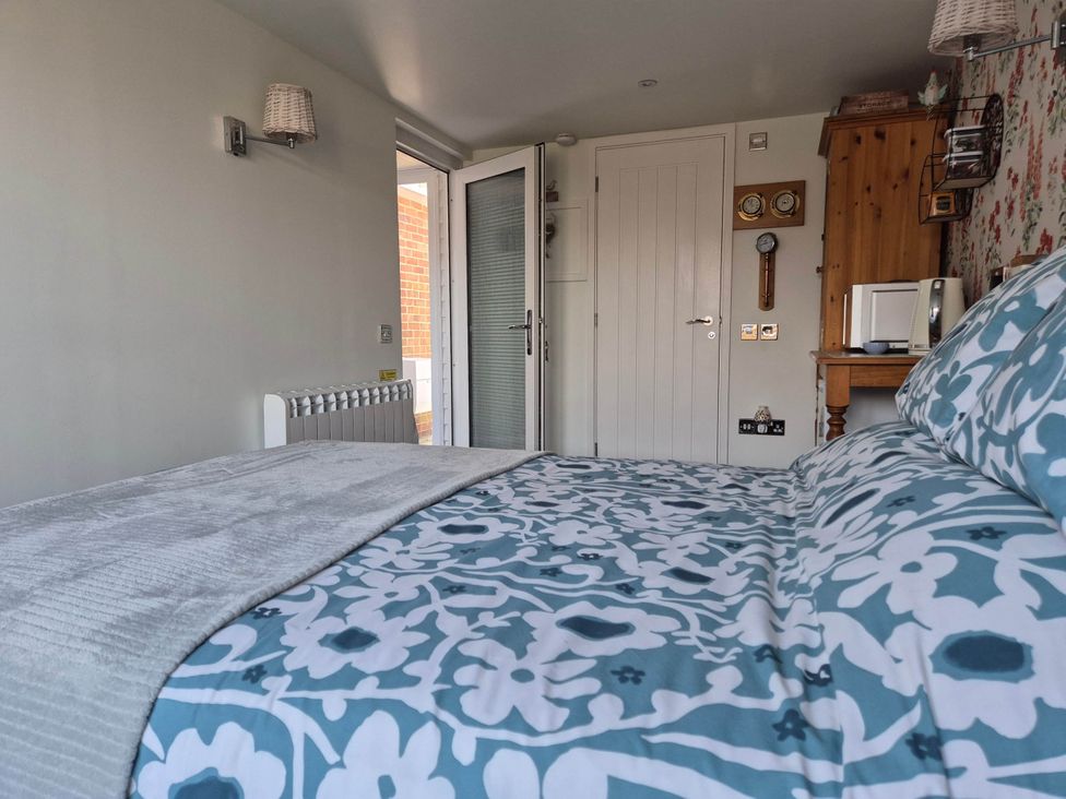 A bedroom with a bed and door at Flower Garden Studio in Sheringham
