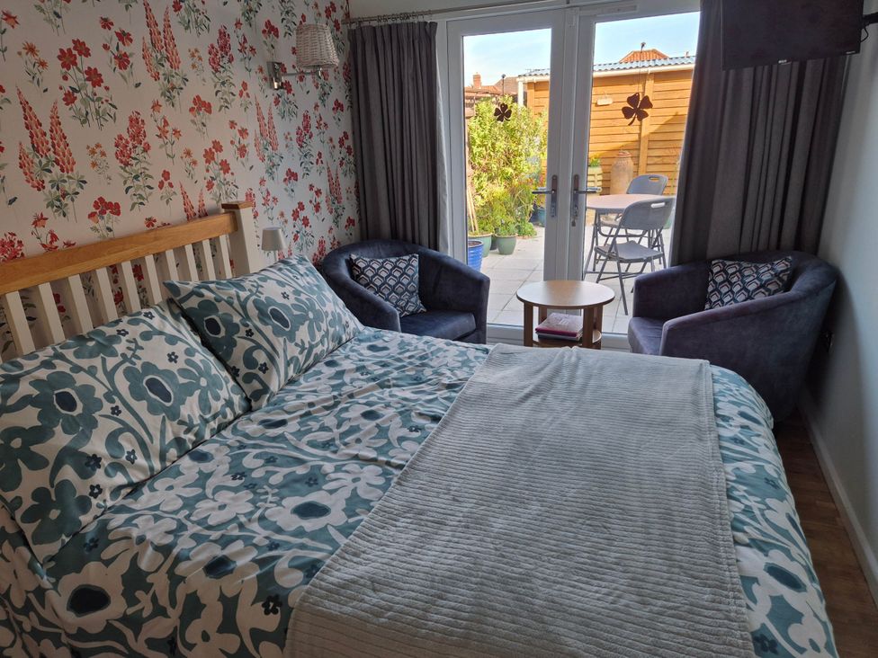 A bedroom with a bed and chairs overlooking a garden at Flower Garden Studio in Sheringham