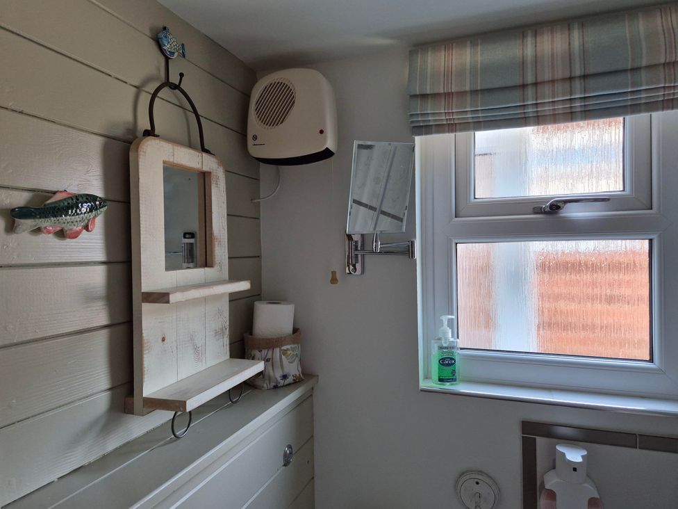 A bathroom with a shelf and mirror at Flower Garden Studio in Sheringham