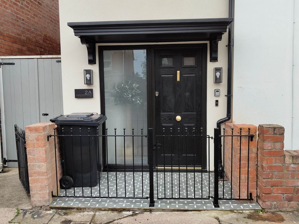 An outdoor entrance with a front door and fence at Luxury 2 Bed Home w/ Spa-like Ensuites & Patio in Hereford